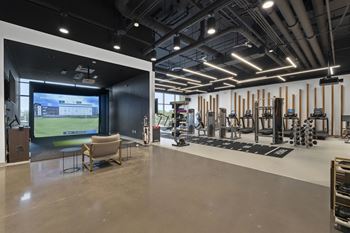 A gym with a large screen on the wall and exercise equipment